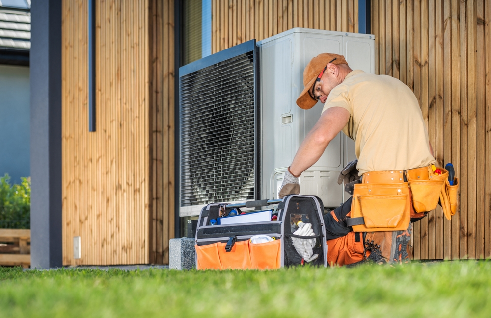 HVAC technician working on a heat pump outside a home